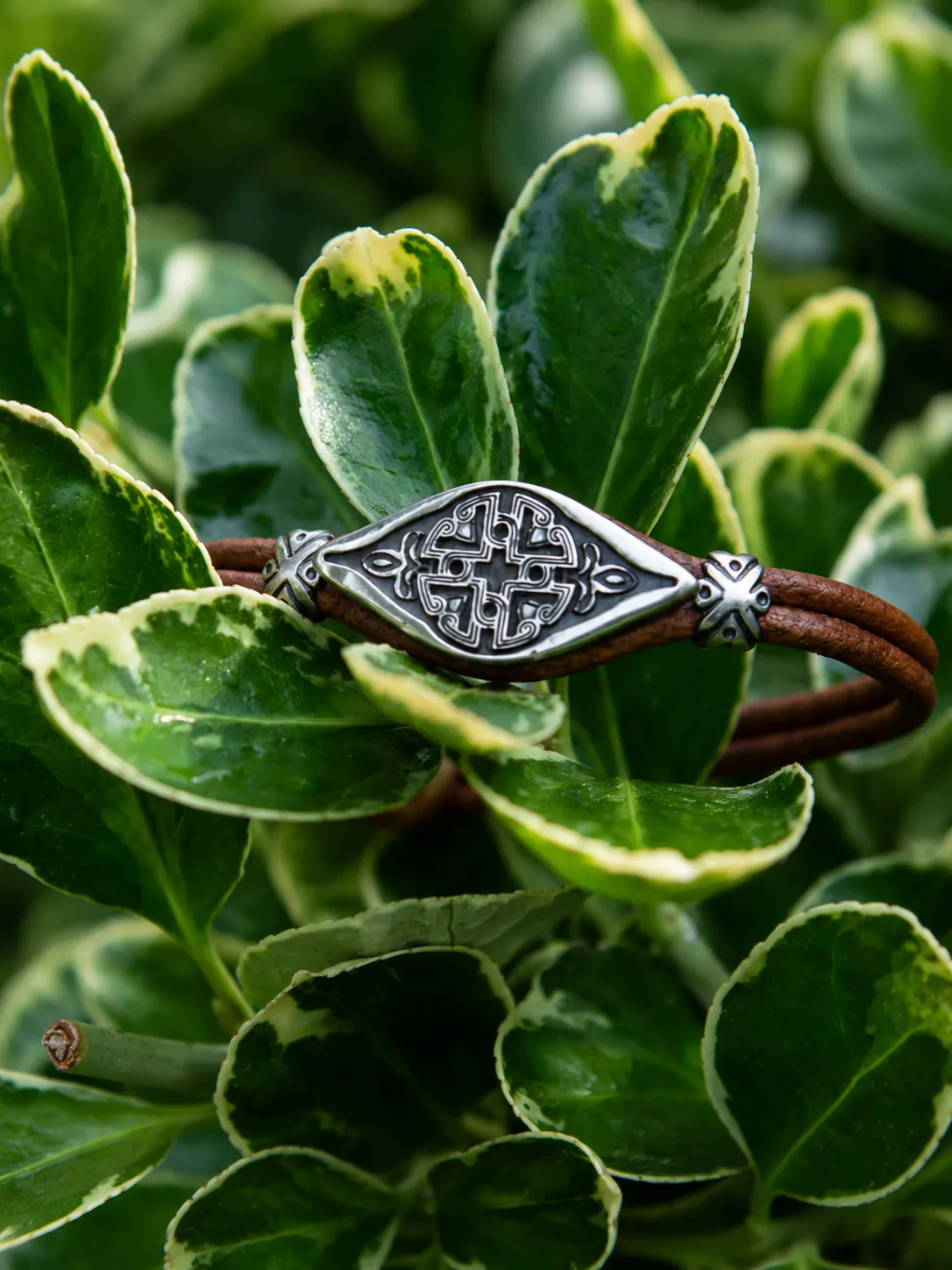 Handcrafted bu-neba silver bracelet resting on green leaves in natural sunlight